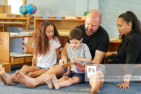 Barefoot family reading book on floor at home
