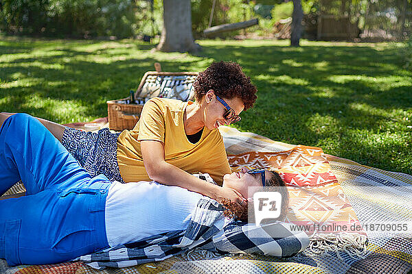 Happy lesbian couple relaxing  cuddling on picnic blanket in park