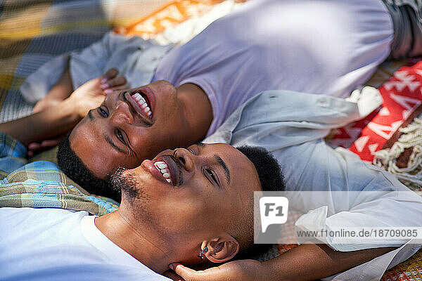 Close up happy  affectionate young gay male couple laying on blanket