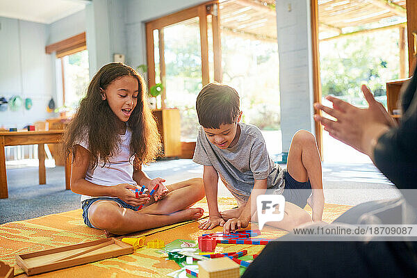 Sister and brother with Down Syndrome playing with toys on floor