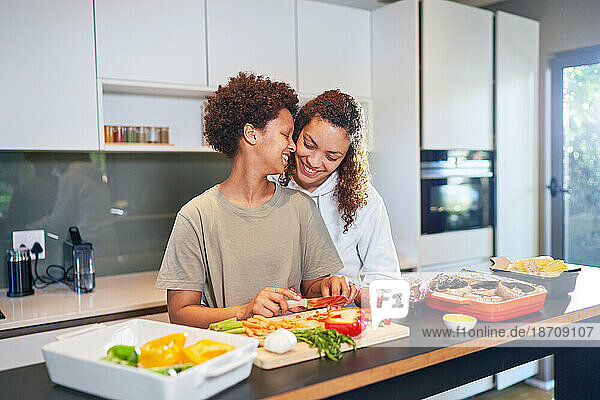 Happy  affectionate lesbian couple cooking fresh vegetables in kitchen