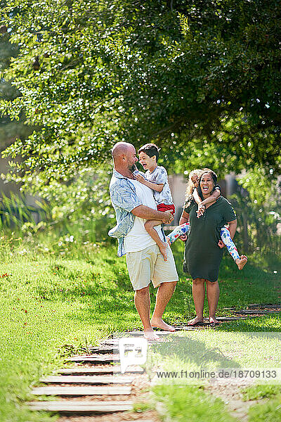 Happy family walking on footpath in sunny summer park