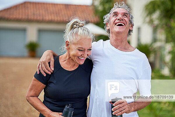 Happy  carefree senior couple with water bottles laughing