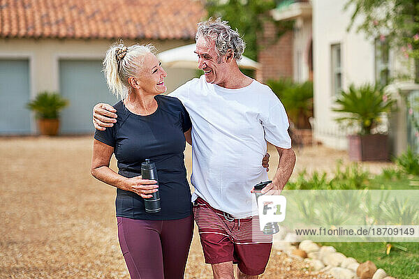Happy  active senior couple hugging and walking outside villa