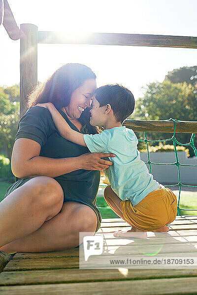 Happy mother and son at sunny playground structure