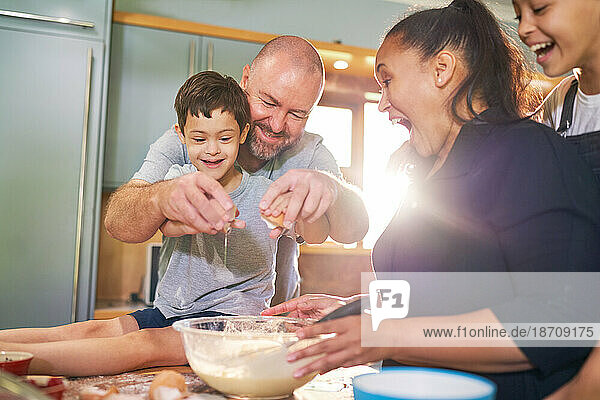 Happy boy with Down Syndrome baking with family in kitchen