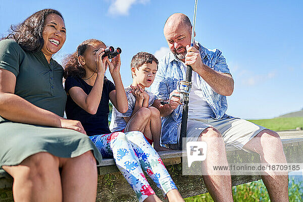 Happy family with binoculars fishing on summer pier