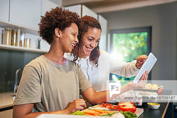 Happy lesbian couple with digital tablet cooking  looking at recipe