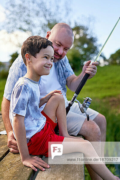 Father and happy son with Down Syndrome fishing on dock