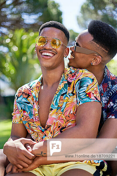 Happy young gay male couple in sunglasses hugging and laughing