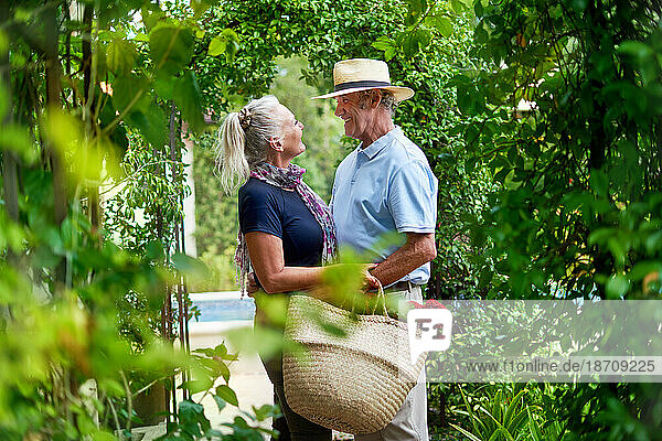 Happy senior couple hugging under lush green trellis in summer garden