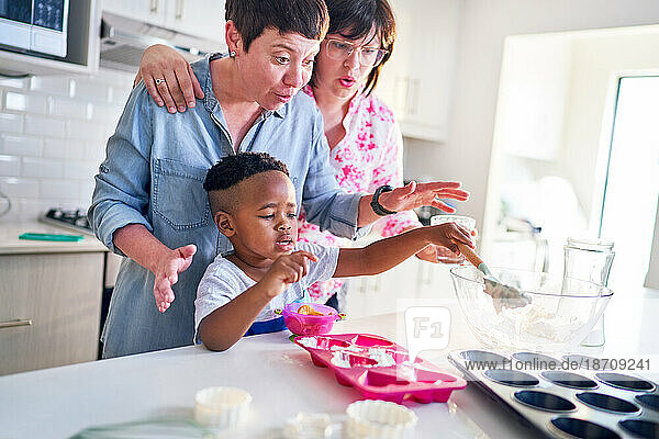 Lesbian couple and cute son baking heart-shape cupcakes in kitchen