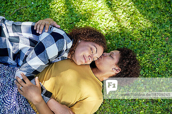 View from above affectionate  serene lesbian couple laying in grass