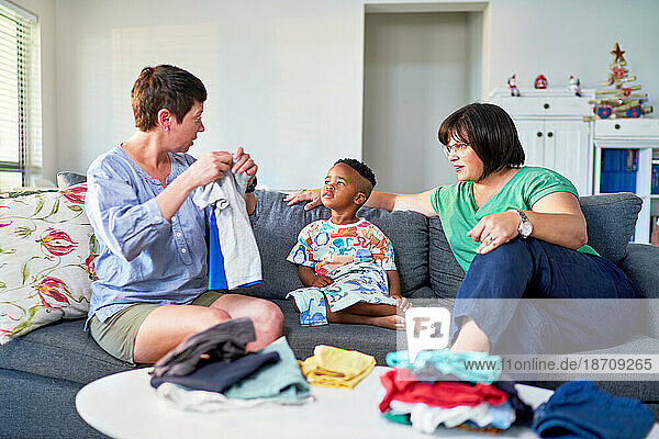 Lesbian couple and son folding laundry and talking in living room
