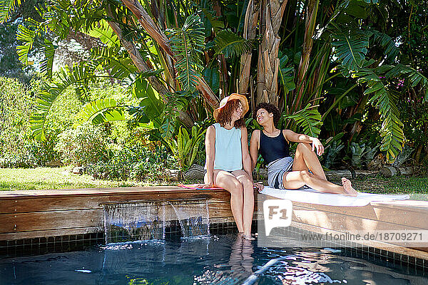 Happy lesbian couple relaxing at tropical summer swimming pool