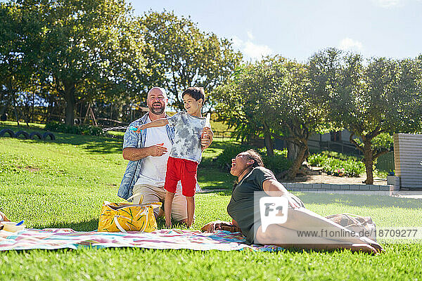 Happy family relaxing and playing with bubbles in sunny summer park
