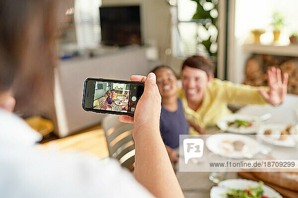 Woman with camera phone photographing wife and son at dinner table