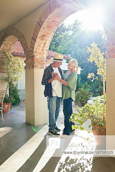 Happy  affectionate senior couple dancing on sunny villa patio