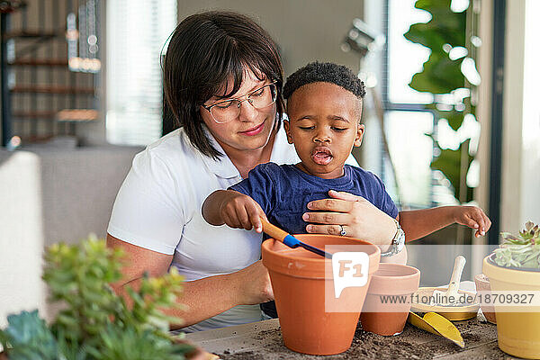 Mother and son planting plants in flowerpots on patio