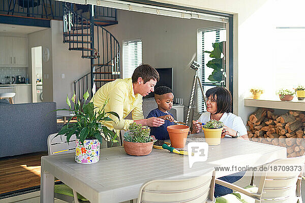 Lesbian couple and son planting plants in flowerpots on patio