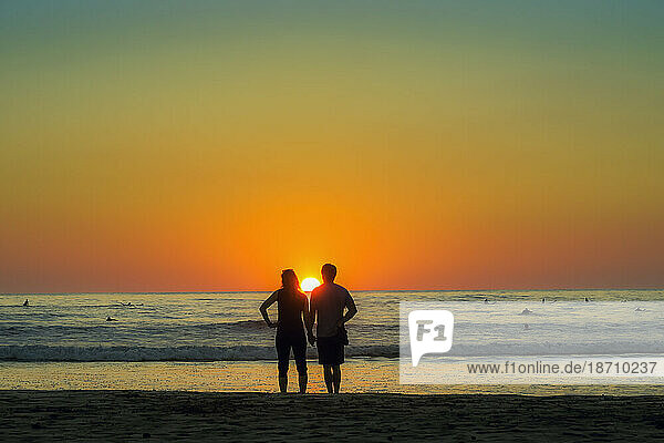 Couple hold hands on Guiones Beach where people gather to surf and watch at sunset  Playa Guiones  Nosara  Guanacaste  Costa Rica  Central America