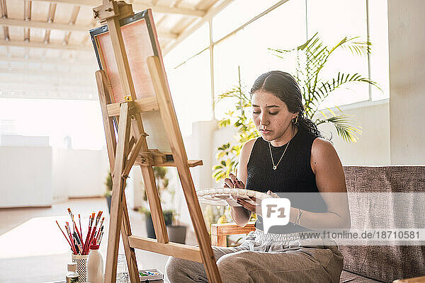 Artist woman painting on canvas. Natural light