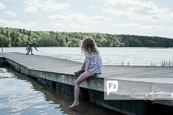young girl watching her brother fish at the beach
