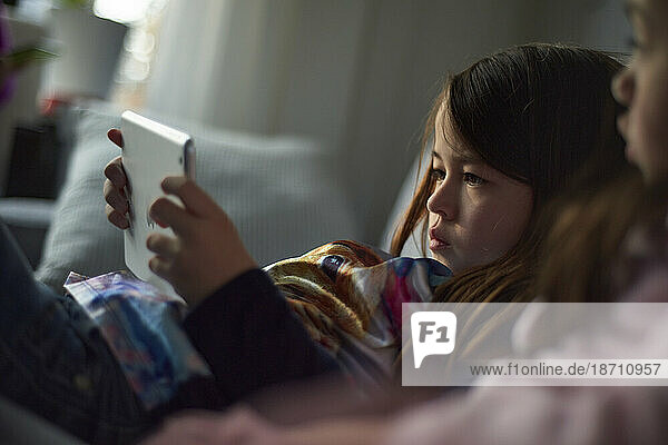 Young Asian girl on the sofa playing with her tablet at home
