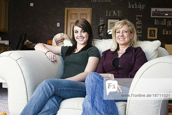 Two women relax in an oversized arm chair.