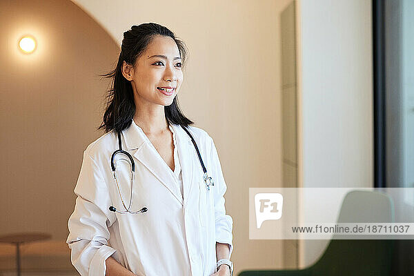 Smiling female doctor with stethoscope standing in clinic