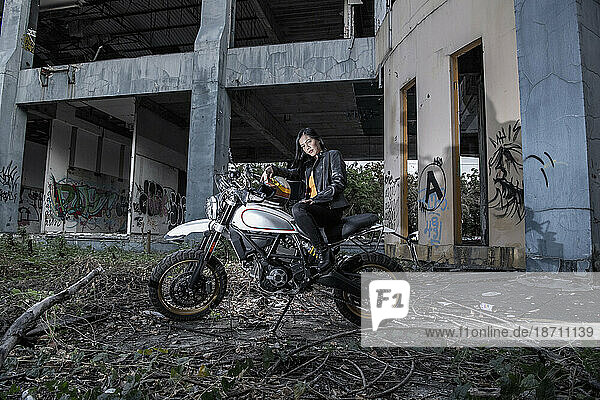 Woman posing on scrambler type motorcycle in abandoned building