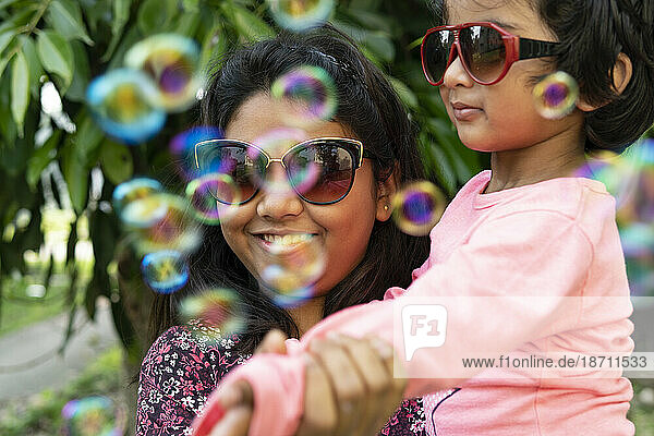Sisters making fun with soap bubbles at outdoors