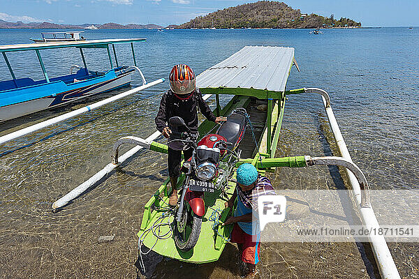 Two men with motorcycle on outrigger boat  Lembar  Lombok  Indonesia