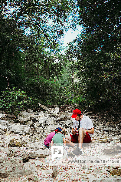 Dad helping daughter and son look for rocks while hiking