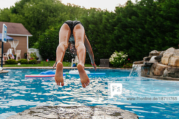 Behind shot of girl diving off rock into swimming pool