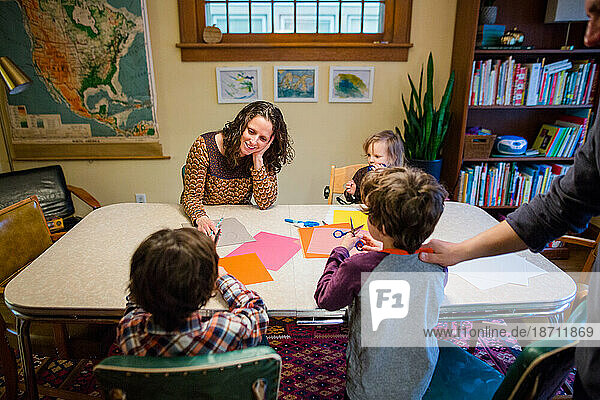 A happy family makes paper craft together at the dining room table