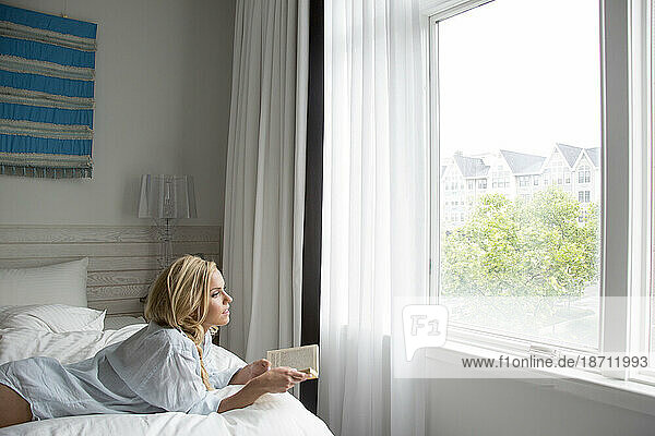 blonde reading a book gazing out window