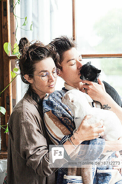 queer couple at home gently cuddling their two chihuahuas