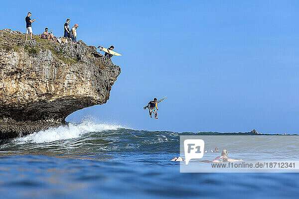 Surfers jumping form cliff into sea  Jimbaran  Bali  Indonesia