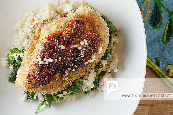 An organic cooked chicken breast sits atop a bed of couscous and spinach in a bowl in a Seattle   Washington  home.
