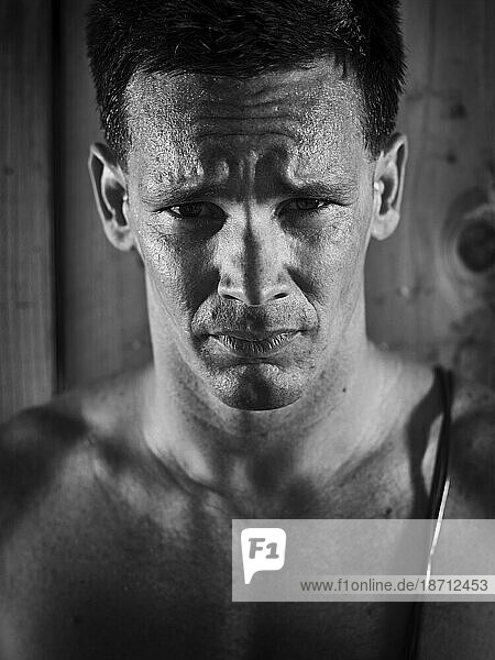 Black and white portrait of a man sweating after a workout.