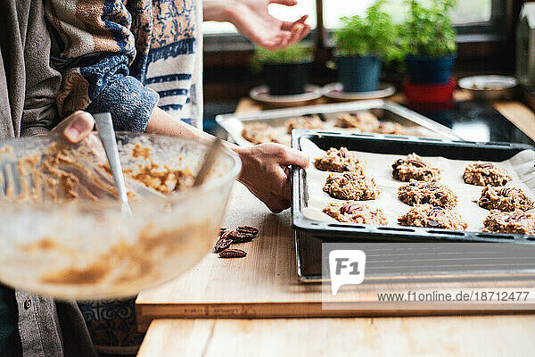 Detail of couples hands lifting fresh tray of cookies at home bake