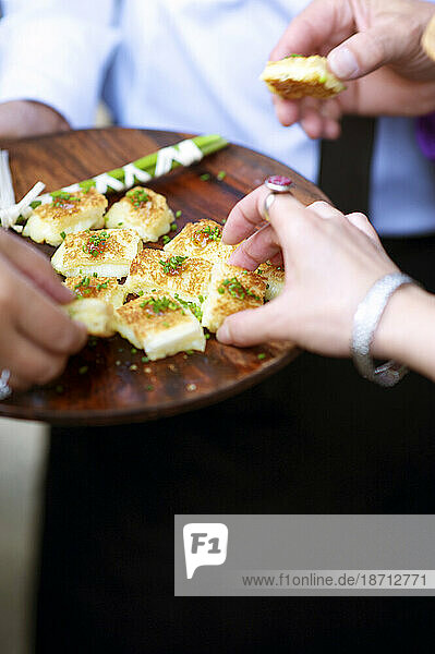 A woman takes an hors d'oeuvre from a plate during a wedding.