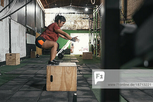 Latin woman box jumping in gym doing crossfit. Perú.