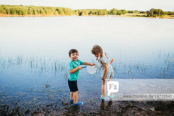 Young boy showing girl a fish he caughte in water at the lake