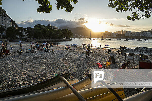 View from Urca Beach during sunset time with people and canoes
