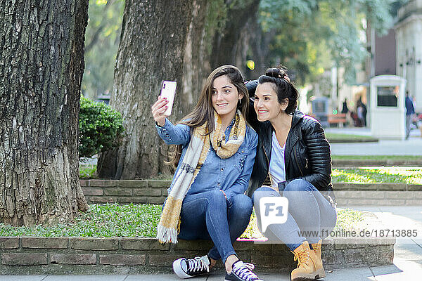 Women sitting on the street taking a selfie