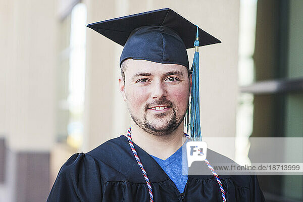 Smiling portrait of male graduate in black cap and gown