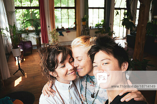 Sweet happy portrait of queer female thrupple at home with plants
