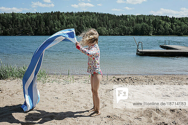 young girl shaking her towel at the beach in Sweden